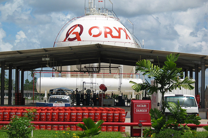 Large spherical gas storage tank labeled "ORYX" with red gas cylinders in front.