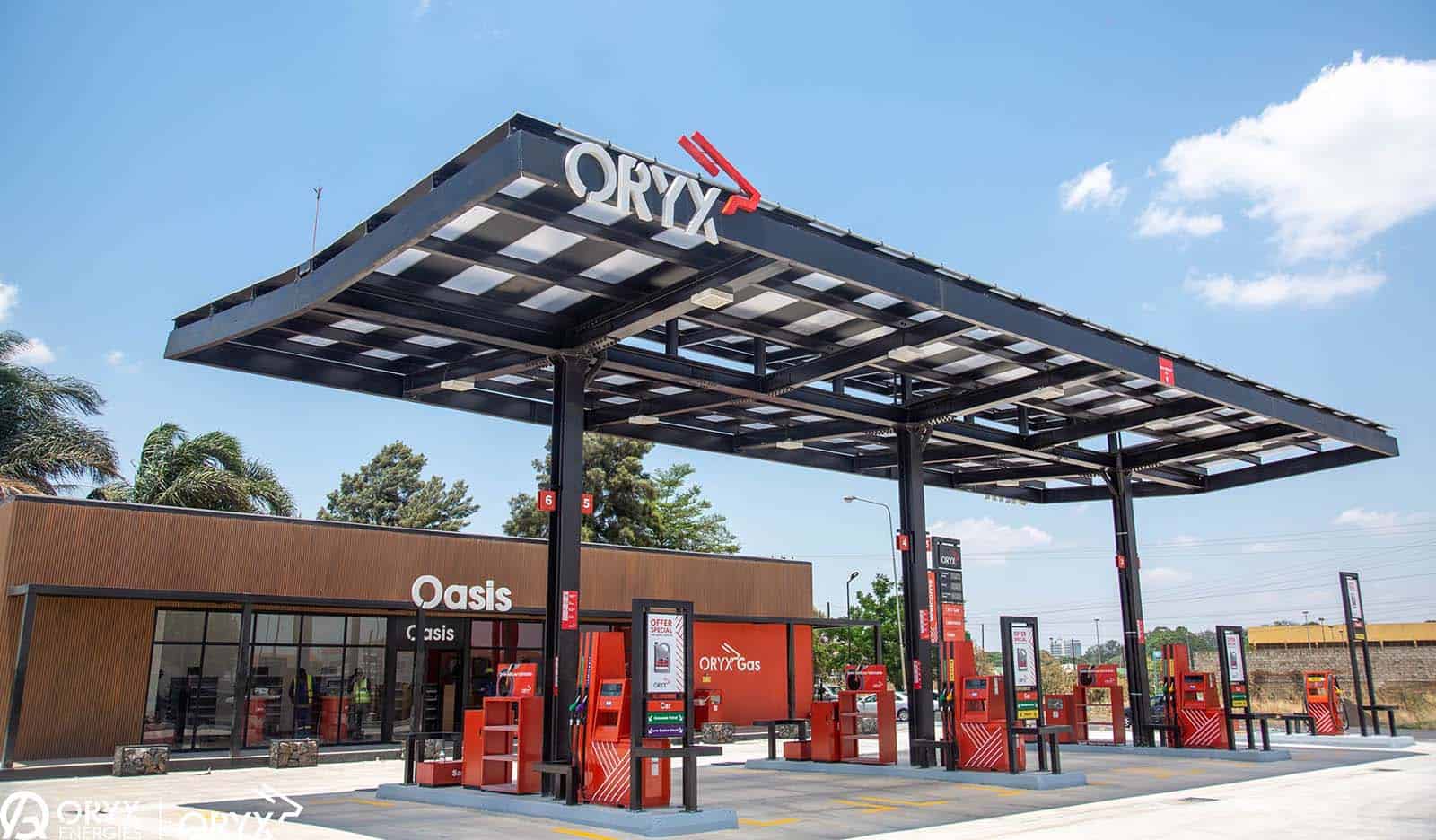 Modern Oryx gas station with red fuel pumps under a large canopy on a sunny day.