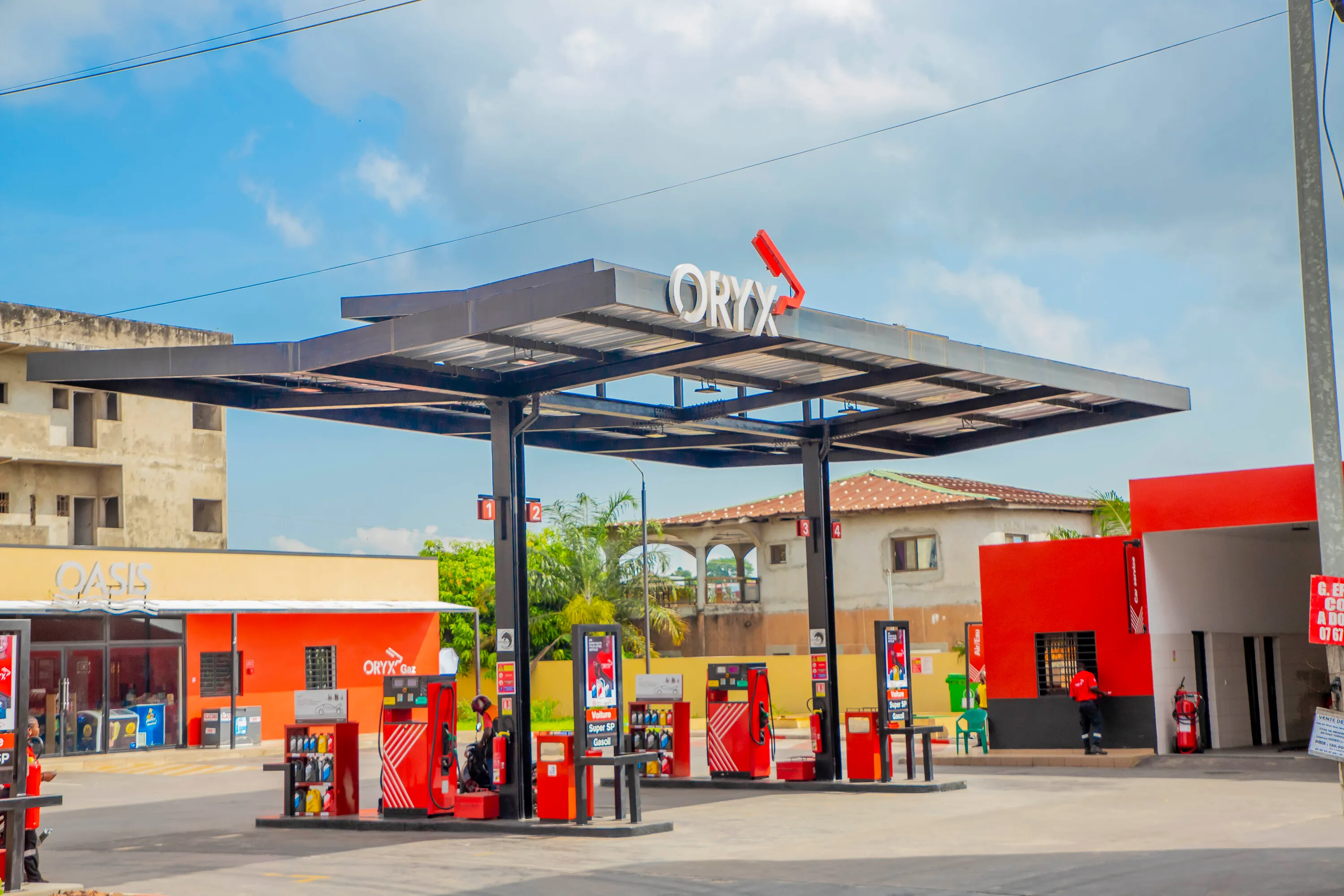 Oryx gas station with red fuel pumps and a convenience store on a sunny day.