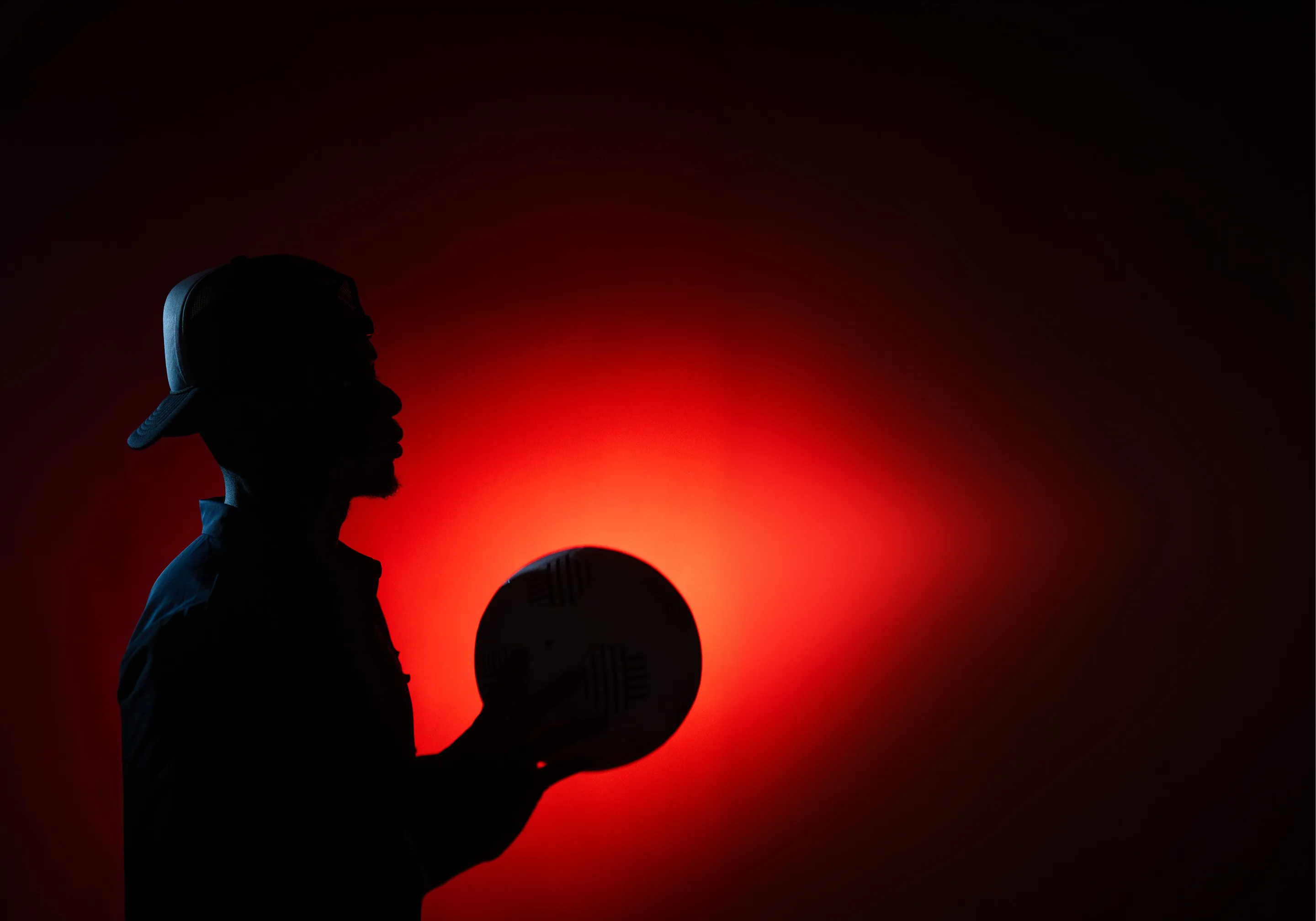 Silhouette of a person holding a basketball against a red glowing background.