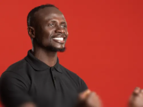 Smiling man in a black polo shirt against a bright red background.